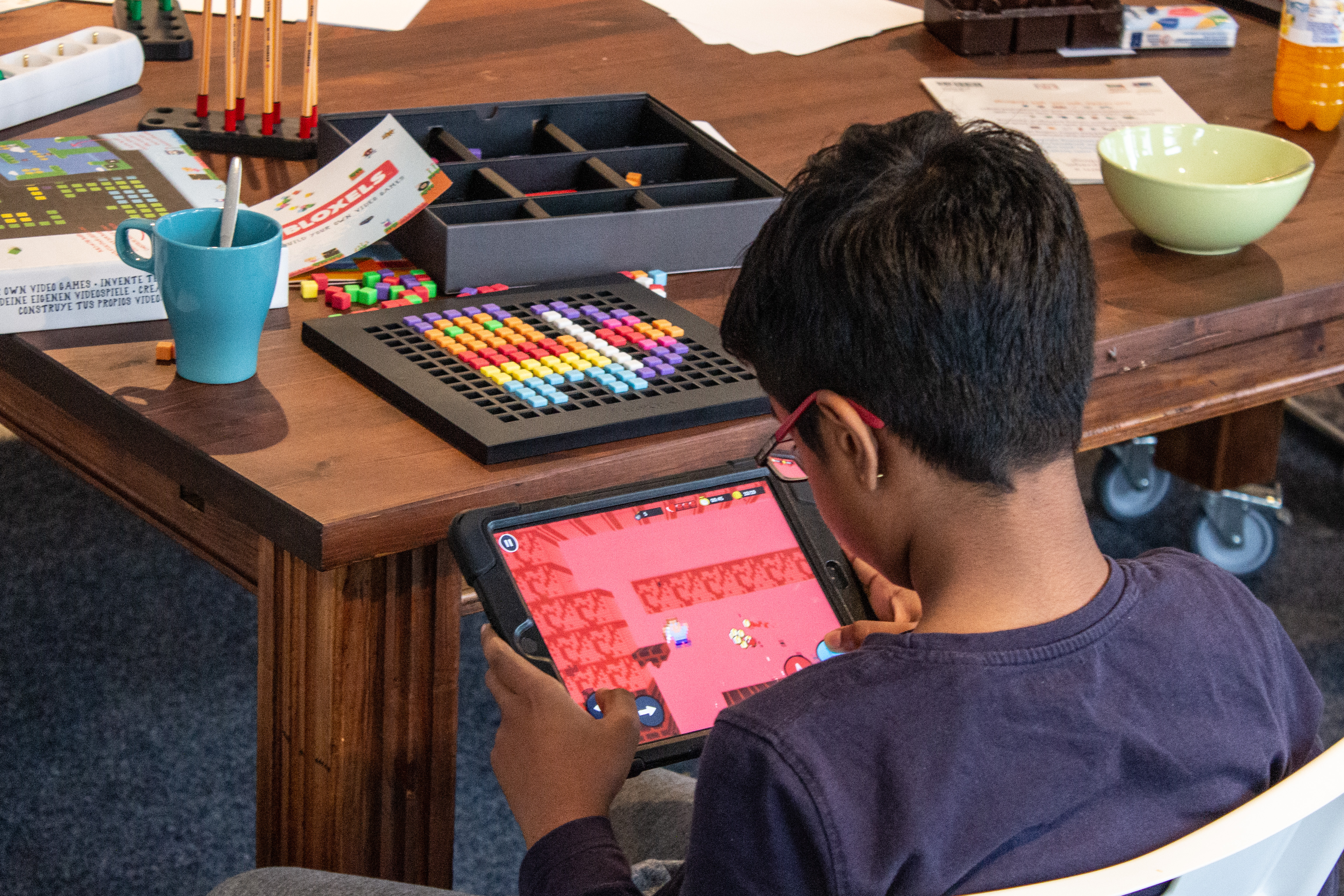 Junge mit Tablet, auf dem ein Spiel in Bloxels zu sehen ist.